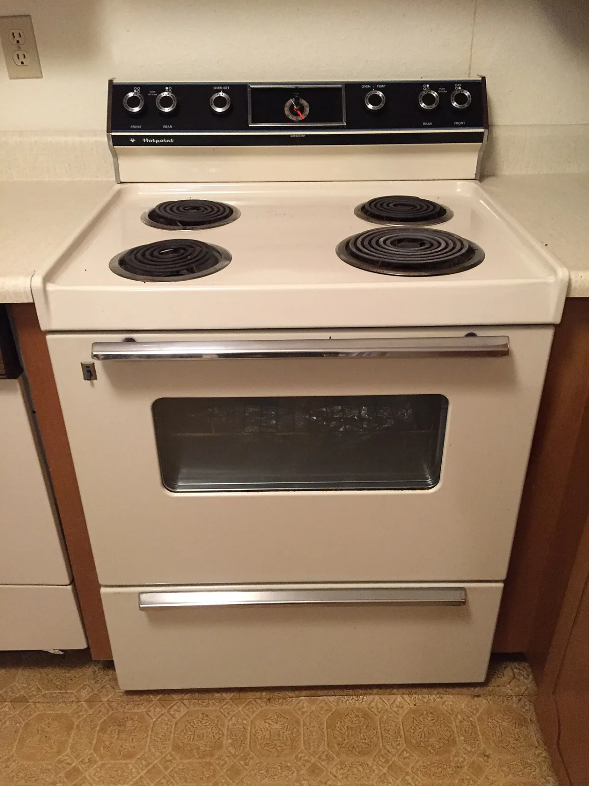 A white Hotpoint electric range with four coil burners and a black control panel, in a home kitchen.