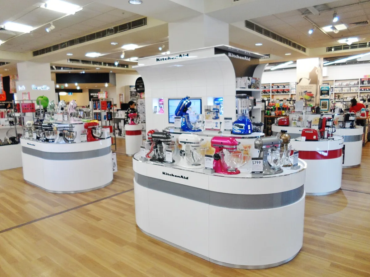 A store display of KitchenAid stand mixers in many colors on white island counters.