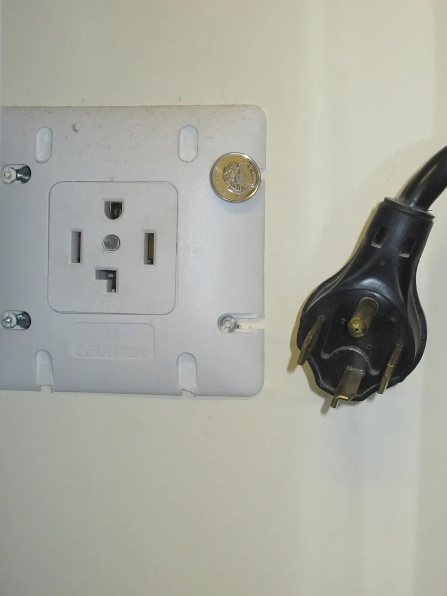 A four wire 240 volt dryer outlet on a wall next to the matching black dryer plug with four prongs