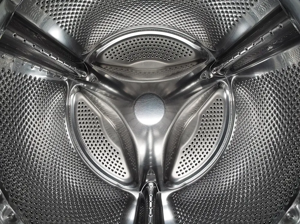 Close-up of the perforated stainless steel drum of a front-loading washing machine